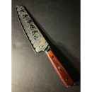 The Spaceman Knives Interstellar Kiritsuke Knife features a patterned Damascus steel blade and polished wooden handle, resting on a dark surface to highlight Spaceman Knives' artisan craftsmanship.