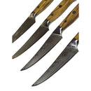 Four Spaceman Knives Interstellar Series steak knives by Spaceman Knives, featuring Damascus blades and olive wood handles, are arranged in parallel on a marble surface to highlight their detailed engravings.