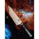 The Spaceman Knives Interstellar Chef Knife by Spaceman Knives, featuring a patterned blade and a black hexagonal handle, floats against a vibrant nebula and star-filled space background.