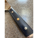 Close-up of the Spaceman Knives Interstellar Kiritsuke Knife handle with a black hexagonal pattern and three rivets, one featuring a decorative circular design, resting on a speckled countertop.