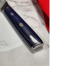 Close-up of the Spaceman Knives Interstellar Petty Chef Knife handle, featuring a blue honeycomb pattern and metal inlays, resting on white marble beside a red cloth.
