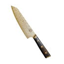 The Spaceman Knives Interstellar Kiritsuke Knife by Spaceman Knives features a stunning Damascus-finish blade and a dark, textured handle with gold accents, beautifully showcased against a white background.