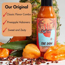 A bottle of Culture Hot Sauce The Don by Culture Hot Sauce stands next to a pineapple, habanero peppers, Szechuan peppercorns, and other spices. The box showcases flavors including Classic Flavor Combo, Pineapple Habanero Hot Sauce—crafted from the original recipe—and Sweet and Zesty.