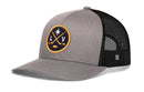 Grey and black Haka Hat Las Vegas Hockey Trucker Hat | LV X Snapback featuring a circular patch with crossed hockey sticks, a puck, a star, and the letters L and V.