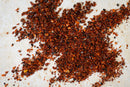 World Spice Limón-Chile, a zesty dried red chili flake blend from World Spice, is scattered across a light-colored, textured surface.