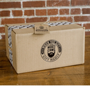 DDR BBQ Supply Manly Cans SmoCAN Hot Gift Can in a branded cardboard box on a rustic wooden table.