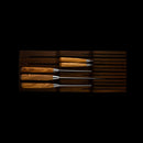 A set of six knives with wooden handles is arranged in the Messermeister In-Drawer Knife Holder - 11 Slot, by Messermeister, displayed in a dark tray against a black background.
