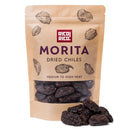 A brown resealable bag labeled Rico Rico Chipotle Morita Dried Chiles – Smoky & Medium Heat Mexican Peppers, featuring illustrations of chiles; a few smoky Chipotle Morita dried peppers are arranged in front of the bag—perfect for bringing an authentic Mexican flavor to your dishes.