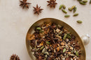 A golden bowl brimming with World Spice Mulling Spice by World Spice—an aromatic mix of star anise, cardamom pods, cloves, and citrus peels—rests on a light surface surrounded by scattered spices and a decorative ornament, ready to create the ultimate mulled wine or cider.