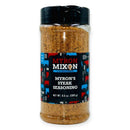 A plastic shaker bottle of Myron Mixon Steak Seasoning with a black lid features a black label with colorful cow silhouettes and white text displaying the Myron Mixon brand and steakhouse-style flavor details.
