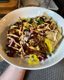 A bowl of nachos topped with shredded meat, BBQ sauce, red onions, banana peppers, cheese, cilantro, and Terrapin Ridge Farms Buffalo Ranch Squeeze. Tortilla chips peek out beneath the flavorful toppings.