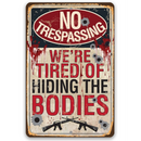 The No Trespassing Tired of Hiding The Bodies - Metal Sign by Lone Star Art features bullet holes, blood splatters, guns, and bold text—a darkly funny gun-themed decor piece.