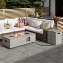Outdoor patio with a wicker sectional sofa, white cushions, pillows, a DirectDeals 42 Inch 50 000 BTU Outdoor Rectangular Fire Table with Tank Holder, small side table on gray tile, and wood privacy fence in the background.