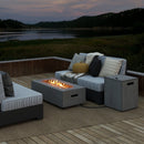 Modern outdoor seating area with cushioned sofas, a DirectDeals 42 Inch 50 000 BTU Outdoor Rectangular Fire Table with Tank Holder, and side table on a deck overlooking a peaceful lake at dusk, hills in the background, blankets and pillows on sofas.