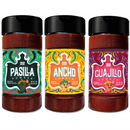Three spice jars from the Rico Rico Chile Powder 3 Pack Bundle—Ancho, Guajillo, and Pasilla—feature colorful, artistic labels and sleek black lids. Each jar is filled with richly hued Ancho chile powder, Guajillo chile powder, or Pasilla chile powder.