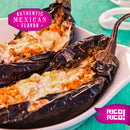 Two roasted eggplants stuffed with melted cheese and meat, served in a white dish and finished with an authentic mole negro made from Rico Rico Pasilla Dried Chiles – Mild & Rich Mexican Chile Negro from Oaxaca. Pink banners display “Authentic Mexican Flavor” and “Rico Rico” on a turquoise wooden table—an irresistible taste that truly captures the essence of Oaxaca.
