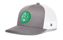 The Haka Hat Philadelphia Football Trucker Hat | Kelly Green PHI X Snapback by Haka Hat is a gray and white trucker hat with a green circular patch on the front showcasing crossed lines, the letters P, H, and I, plus a small football icon. Designed for comfort, this Philadelphia Football Trucker Hat features white mesh back panels for breathability and a classic snapback closure for an adjustable fit.