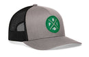 The Haka Hat Philadelphia Football Trucker Hat | Kelly Green PHI X Snapback features a gray and black mesh snapback design with a green circular patch displaying crossed lines, the letters P, H, I, and a small football icon in the center—perfect for fans seeking a stylish Philadelphia Football Trucker Hat.
