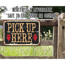 The Lone Star Art Pick Up Here - Metal Sign features two red arrows on a rustic wooden fence. Beautiful and affordable, it’s safe for indoor or outdoor use—ideal restaurant signage set against grass and wildflowers.