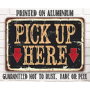 The Lone Star Art Pick Up Here - Metal Sign features two red arrows pointing down and a distressed vintage style. Made from rustproof aluminium, this indoor/outdoor sign won’t fade or peel—ideal for restaurant use.