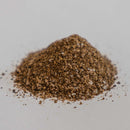 A small pile of Dead Rooster Co. Black Gold Coffee Rub sits on a white surface, displaying a mix of fine and coarse particles—perfect for bringing bold flavor to your favorite steak rub or brisket seasoning.
