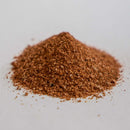 A small mound of finely ground brownish-red Dead Rooster Co Redwood BBQ Rub sits on a plain white surface, ready to add bold flavor to smoked meats or help you create an authentic Kansas City barbecue experience with Dead Rooster Co. seasoning.