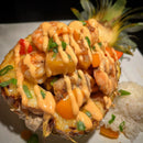 Shrimp, bell peppers, and pineapple chunks served in a pineapple half, drizzled with Terrapin Ridge Farms Bang Bang Squeeze, garnished with green onions and paired with white rice on a white plate.