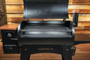 A black Pit Boss Austin XL pellet grill with its lid open, revealing a Pimp My Grill® Gen2 Slide-Out Rack System with two stacked, rectangular metal wire cooking racks inside.
