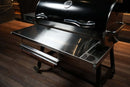 Pimp My Grill Tactical Stainless Folding Front Shelf attached to a RecTeq RT-700 pellet grill, featuring a side utility tray and an integrated paper towel holder.