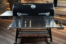 A Pimp My Grill® Tactical Stainless Folding Front Shelf attached to a black pellet grill, providing convenient prep space.
