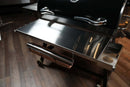 A Pimp My Grill® Tactical Stainless Folding Front Shelf for the Recteq RT-700 / RT-680, featuring a stainless steel design with an integrated paper towel holder and a side accessory tray for added grill prep space.