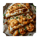 Close-up of folded tortillas filled with sautéed shrimp, drizzled with Rufus Teague Diablo Limonajo BBQ Sauce, and garnished with chopped herbs, served on parchment paper.