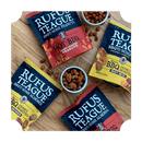 A bag of Rufus Teague Dill Pickle Peanuts sits on a wooden surface, with a small bowl of the peanuts nearby and some scattered around.