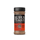 A bottle of Rufus Teague Steak Rub with a black lid and orange label showing the brand, product name, and 12 oz weight; the gluten-free seasoning is visible through the clear container.