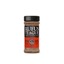 A bottle of Rufus Teague Steak Rub by Rufus Teague, with a black and orange label and steak graphic, stands on a white background. This gluten-free seasoning is ideal for enhancing your favorite cuts.