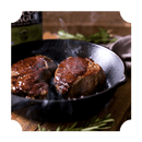 Two seared steaks sizzle in a black cast iron skillet, steam rising as fresh rosemary sprigs rest nearby—perfect for pairing with Rufus Teague Steak Sauce by Rufus Teague for a bold, gluten-free finish.