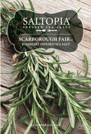 A close-up of rosemary sprigs on wood showcases SALTOPIA Infused Sea Salts' SCARBOROUGH FAIR Rosemary Salt—ideal for savory dishes and herb seasonings. Visit saltopiasalts.com for more.