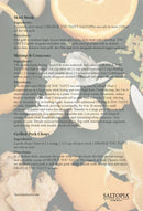 A recipe card with Skirt Steak, Shrimp & Couscous, and Pork Chops recipes appears on a backdrop of ingredients and utensils, featuring the SALTOPIA Infused Sea Salts logo and ORANGE YOU TASTY Orange & Garlic Salt flavor accents.