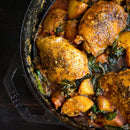 A cast iron skillet of roasted chicken thighs, golden potatoes, and greens in a savory sauce—perfect for healthy cooking with low sodium SALTOPIA Smoky Sweet Mustard Seasoning: MACK'S BACK.