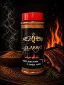 A bottle of Scott’s Smoked Q Classic Dry Rub Sweet Smoky All-Purpose BBQ Seasoning sits beside a bowl of spices and smoked ribs, with flames and smoke in the background. The label reads “Maryland Born, Florida Made.” This seasoning from Scott’s Smoked Q is a sweet and smoky dry rub that’s perfect for elevating all your BBQ dishes.
