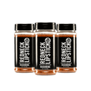 Three bottles of Redneck Lipstick 3-Pack Smoky Sweet & Spicy Seasoning Blend, featuring black labels and lids, are lined up side by side on a white background. The labels read “Smoky, Savory & Spicy Smooth” and “Real Good Seasoning.” This versatile all-purpose seasoning from Redneck Lipstick is perfect as a BBQ rub, delivering smoky, sweet, and spicy flavor to elevate any dish.