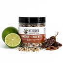 A jar of B.T. Leigh’s Chipotle & Lime Finishing Salt surrounded by a lime, a lime half, and dried chili peppers.