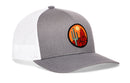 Introducing the Haka Hat Southwest Sunset Trucker Hat—a stylish gray and white snapback from Haka Hat with a breathable mesh back. The front displays a round patch featuring a cactus and red rock desert landscape with an orange sun, capturing the spirit of the Southwest. This Desert Snapback is perfect for anyone seeking an iconic Southwest look.