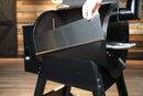 A hand placing a Pimp My Grill® Bodyguard Stainless Steel Grease & Paint Protector along the interior rim of a black pellet grill.