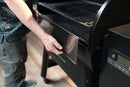 A person installing a Pimp My Grill® Bodyguard Stainless Steel Grease & Paint Protector onto the front edge of a Traeger Pro 780 pellet grill.