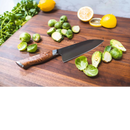 A Steelport Knife Co. 6" Chef Knife rests on a wooden cutting board alongside halved Brussels sprouts, whole Brussels sprouts, parsley, and two halved lemons.
