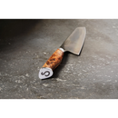 The Steelport Knife Co. 8" Chef Knife, featuring a wooden handle and expertly crafted through traditional forging techniques for outstanding blade edge retention, rests on a gray stone countertop. The end of the handle is adorned with Steelport Knife Co.’s signature circular “S” emblem.