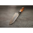 The Steelport Knife Co. 8" Chef Knife, featuring a polished blade and wooden handle, rests on a gray textured surface—highlighting Steelport Knife Co.'s commitment to traditional knife forging and exceptional blade edge retention.