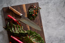 A Steelport Knife Co. Everyday Knife & Board Set is displayed on a wooden cutting board, surrounded by chopped and whole Swiss chard leaves and stalks. The scene is set against a gray stone countertop, emphasizing the craftsmanship of this Made-in-USA kitchen knife from Steelport Knife Co.