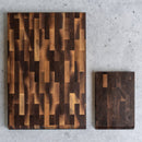 The Steelport Knife Co. Signature Knife & Board Set, featuring two rectangular wooden cutting boards—one large and one small—with a sophisticated patchwork end-grain design, is arranged on a light gray textured surface, creating an elegant backdrop to showcase your handcrafted knives.
